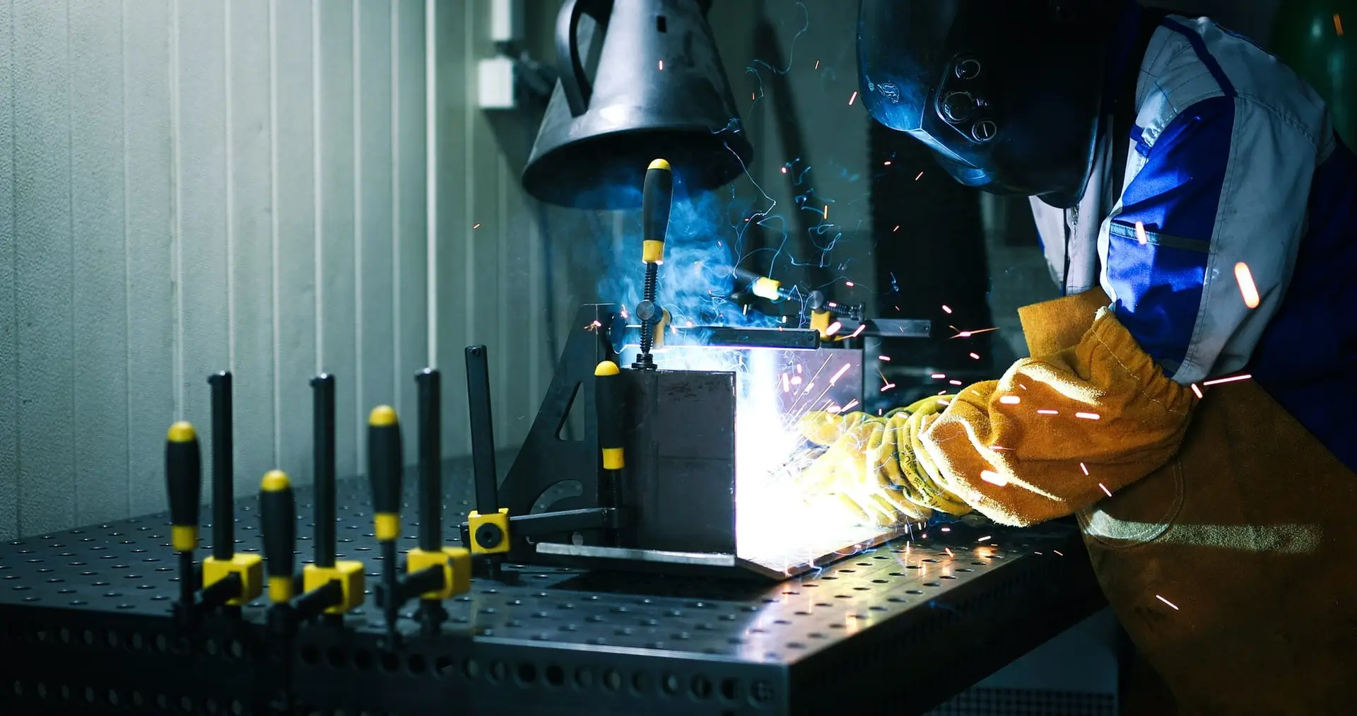 man welds at the factory working in metal industry